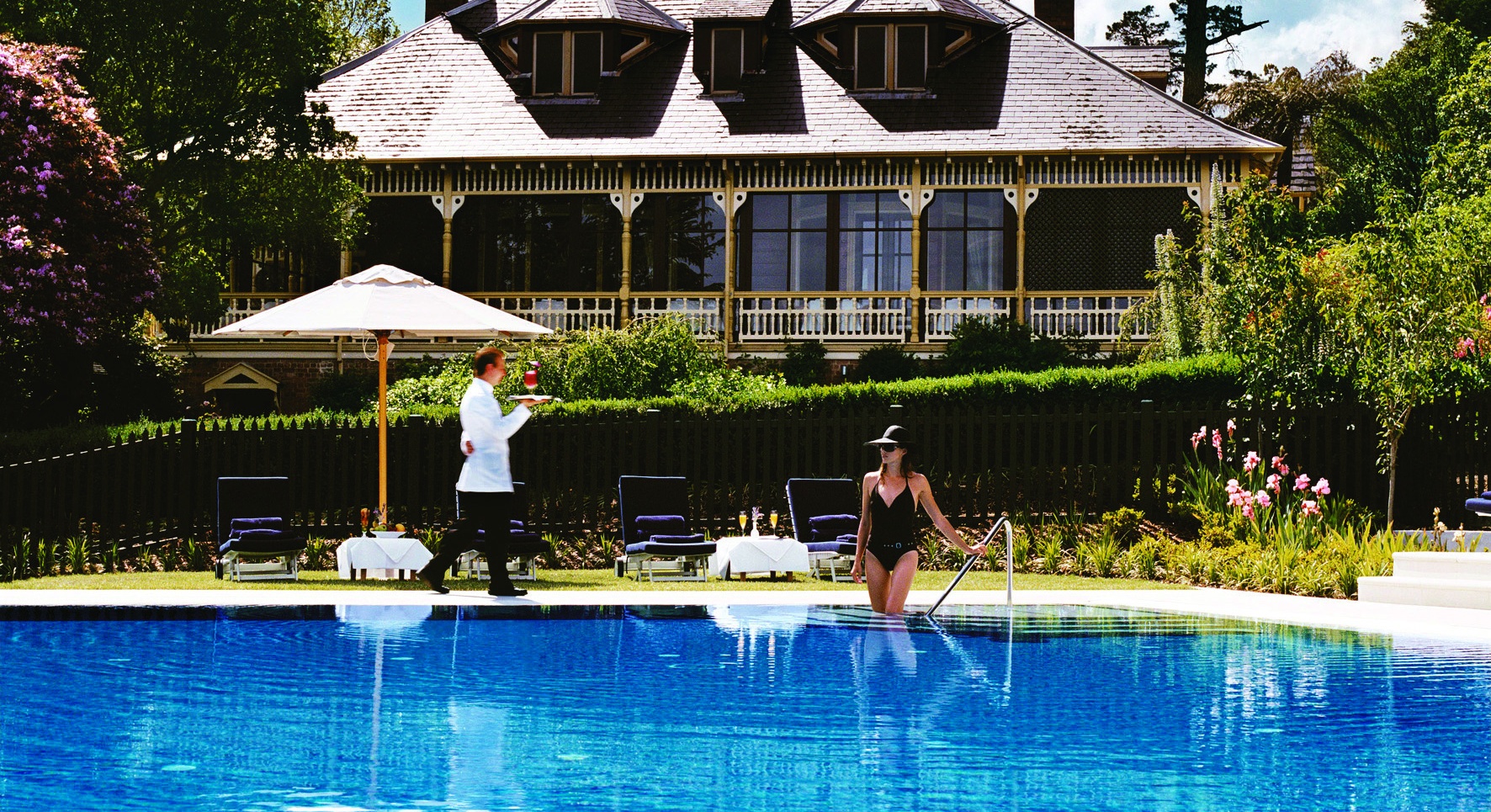 Photo of women entering hotel pool. Waiter in background.